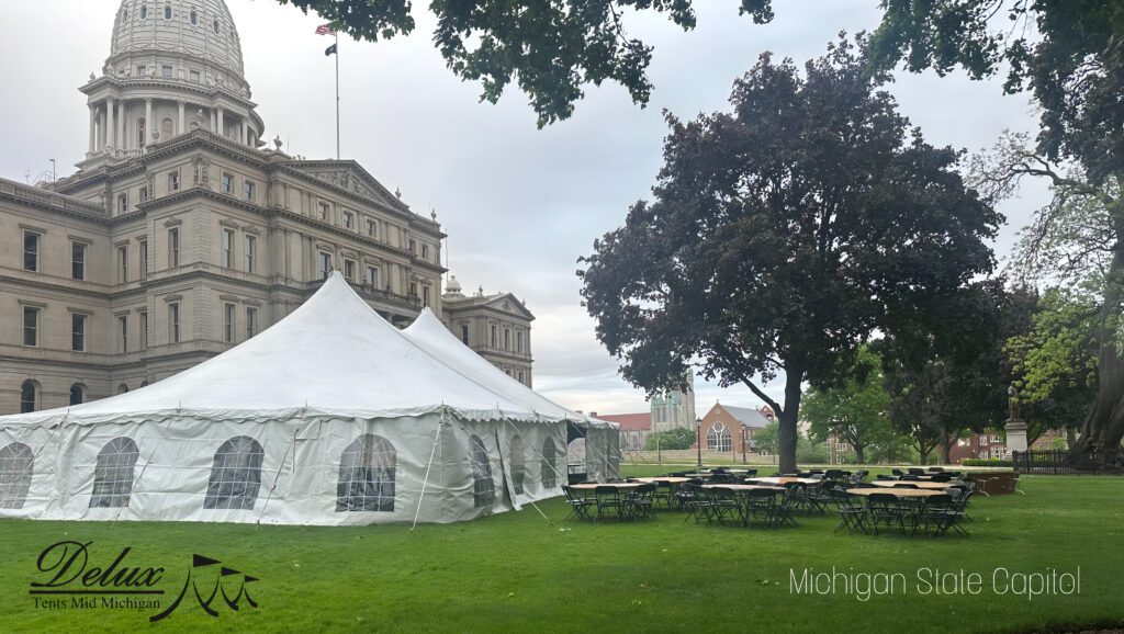An outdoor event setup including a tent and tables set up by Delux Tents Mid Michigan in front of the Michigan Capitol building.