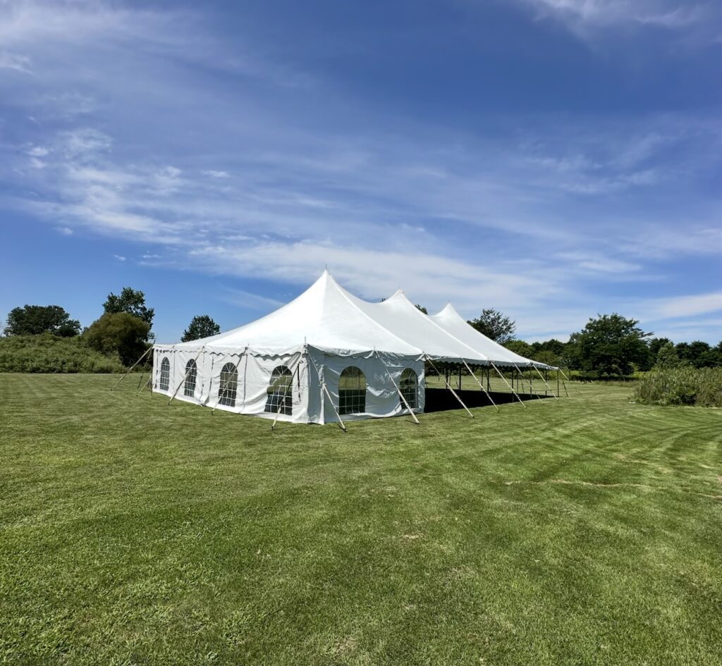 white event tent in grassy green open field under a blue sky