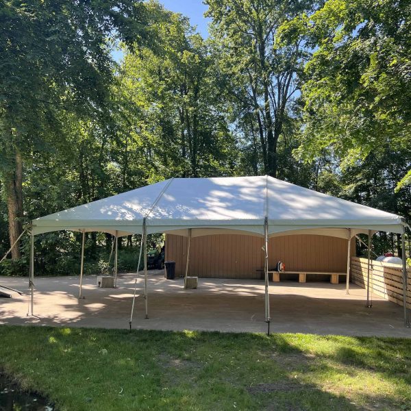 a large white event tent set up on grass with a stage.